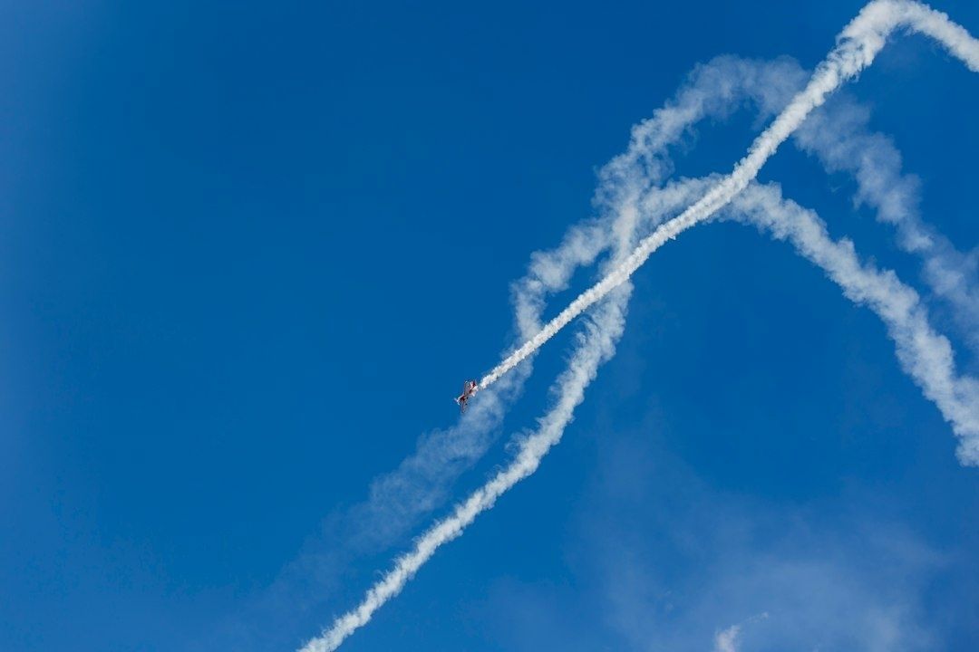 Avion de voltige traçant une large boucle de fumée dans le ciel bleu