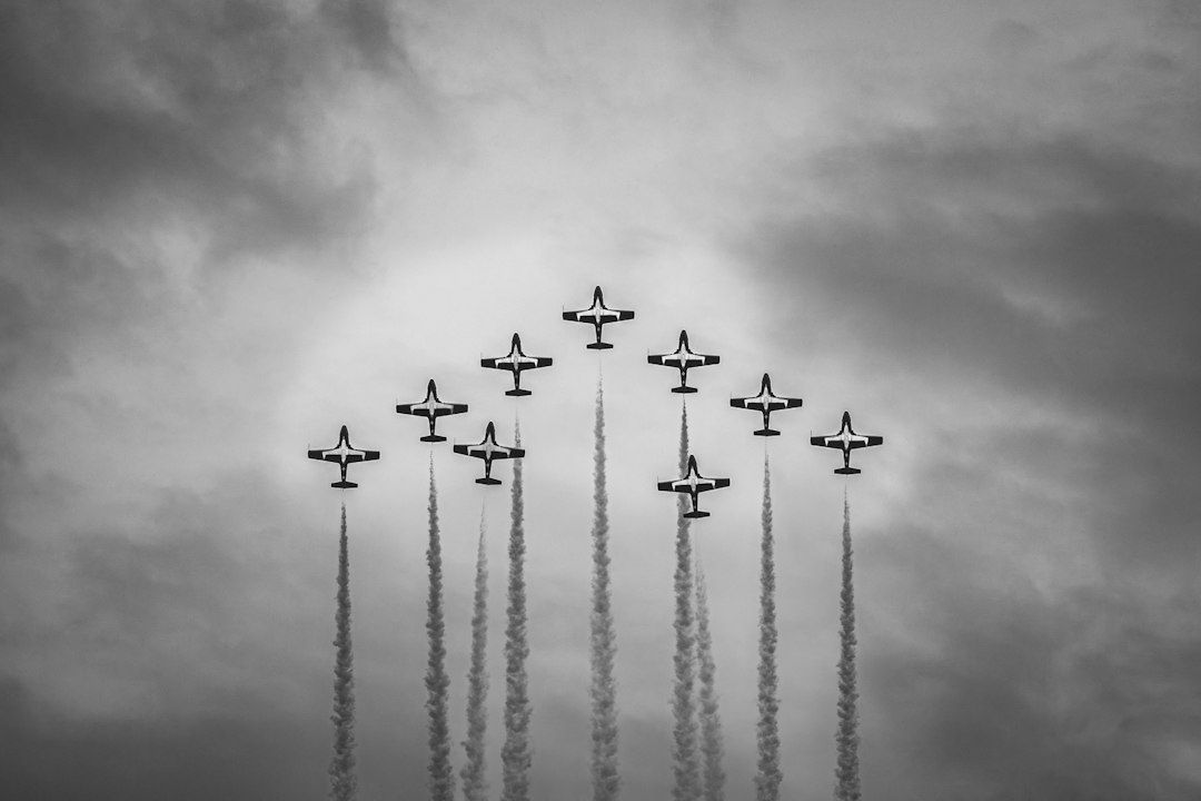 Neuf avions en formation verticale, laissant des traînées de fumée
